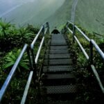 man walking on gray ladder on hill